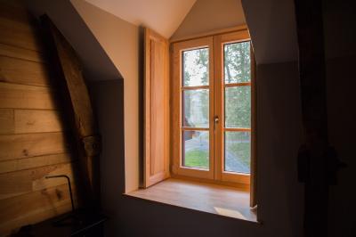 Cabane en bois perchée dans les arbres, entourée de forêt et bordée d'une prairie verdoyante.