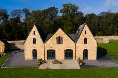 Cabane en bois perchée dans les arbres, entourée de forêt et bordée d'une prairie verdoyante.