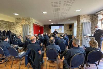 Cabane en bois perchée dans les arbres, entourée de forêt et bordée d'une prairie verdoyante.