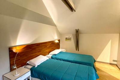 Cabane en bois perchée dans les arbres, entourée de forêt et bordée d'une prairie verdoyante.