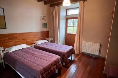 Cabane en bois perchée dans les arbres, entourée de forêt et bordée d'une prairie verdoyante.