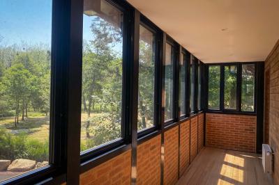 Cabane en bois perchée dans les arbres, entourée de forêt et bordée d'une prairie verdoyante.