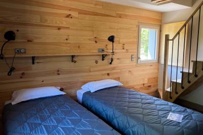 Cabane en bois perchée dans les arbres, entourée de forêt et bordée d'une prairie verdoyante.