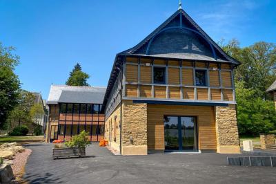 Cabane en bois perchée dans les arbres, entourée de forêt et bordée d'une prairie verdoyante.