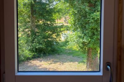 Cabane en bois perchée dans les arbres, entourée de forêt et bordée d'une prairie verdoyante.