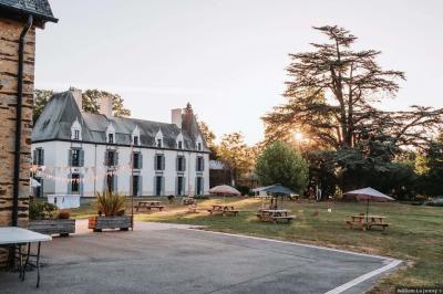 Cabane en bois perchée dans les arbres, entourée de forêt et bordée d'une prairie verdoyante.