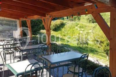 Tables hautes recouvertes de nappes blanches, décorées de bouquets, dans une salle lumineuse avec baies vitrées.