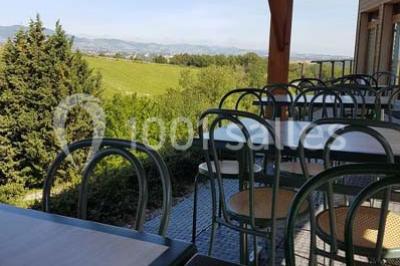 Tables hautes recouvertes de nappes blanches, décorées de bouquets, dans une salle lumineuse avec baies vitrées.