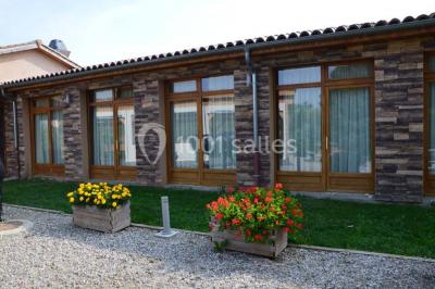Tables hautes recouvertes de nappes blanches, décorées de bouquets, dans une salle lumineuse avec baies vitrées.