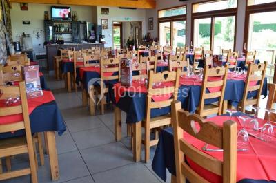 Tables hautes recouvertes de nappes blanches, décorées de bouquets, dans une salle lumineuse avec baies vitrées.