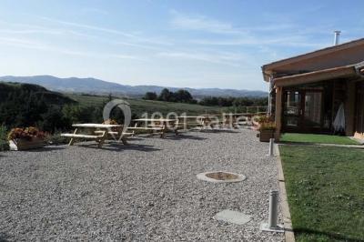 Tables hautes recouvertes de nappes blanches, décorées de bouquets, dans une salle lumineuse avec baies vitrées.