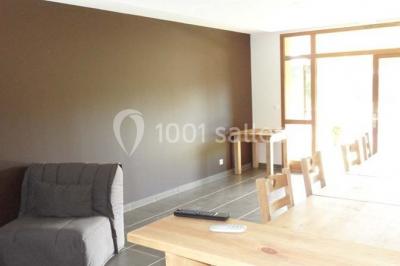 Tables hautes recouvertes de nappes blanches, décorées de bouquets, dans une salle lumineuse avec baies vitrées.