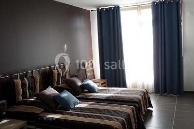 Tables hautes recouvertes de nappes blanches, décorées de bouquets, dans une salle lumineuse avec baies vitrées.