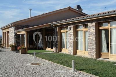 Tables hautes recouvertes de nappes blanches, décorées de bouquets, dans une salle lumineuse avec baies vitrées.