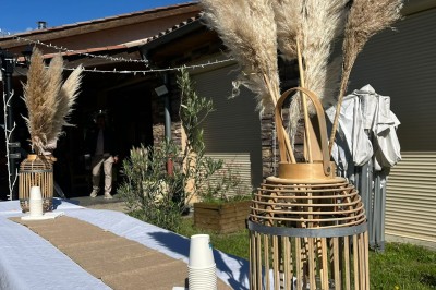 Tables hautes recouvertes de nappes blanches, décorées de bouquets, dans une salle lumineuse avec baies vitrées.