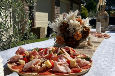 Tables hautes recouvertes de nappes blanches, décorées de bouquets, dans une salle lumineuse avec baies vitrées.