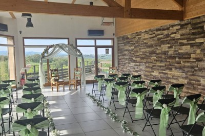 Tables hautes recouvertes de nappes blanches, décorées de bouquets, dans une salle lumineuse avec baies vitrées.
