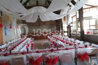 Grande salle lumineuse avec charpente en bois apparente, sol carrelé et murs clairs, éclairée par des fenêtres.