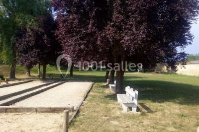 Grande salle lumineuse avec charpente en bois apparente, sol carrelé et murs clairs, éclairée par des fenêtres.