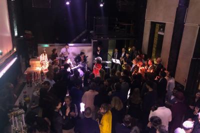 Parking extérieur de nuit, éclairé par des lumières jaunes et entouré d'arbres et de bâtiments.