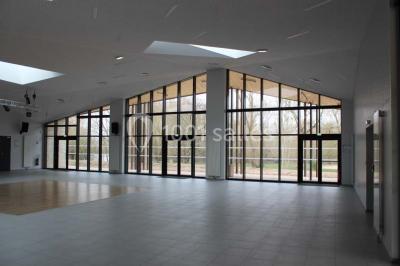 Cuisine professionnelle avec plans de travail en inox, équipements de cuisson, éviers et carrelage mural gris.