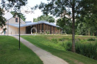 Cuisine professionnelle avec plans de travail en inox, équipements de cuisson, éviers et carrelage mural gris.