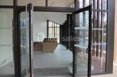 Cuisine professionnelle avec plans de travail en inox, équipements de cuisson, éviers et carrelage mural gris.