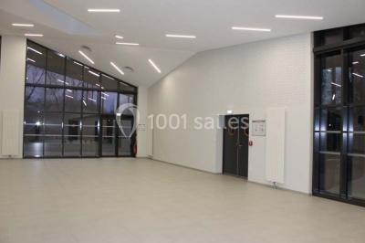 Cuisine professionnelle avec plans de travail en inox, équipements de cuisson, éviers et carrelage mural gris.