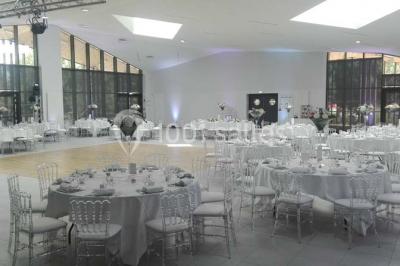 Cuisine professionnelle avec plans de travail en inox, équipements de cuisson, éviers et carrelage mural gris.