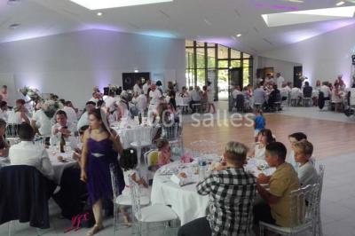 Cuisine professionnelle avec plans de travail en inox, équipements de cuisson, éviers et carrelage mural gris.