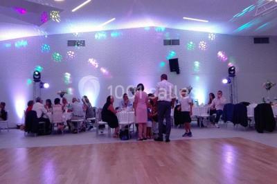 Cuisine professionnelle avec plans de travail en inox, équipements de cuisson, éviers et carrelage mural gris.