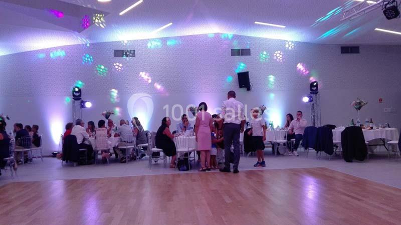 Des convives assis à des tables décorées dans une salle éclairée par des lumières colorées, lors d'un événement festif.