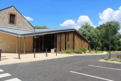 Cuisine professionnelle avec plans de travail en inox, équipements de cuisson, éviers et carrelage mural gris.