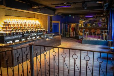 Intérieur d'un restaurant avec des tables, des chaises élégantes, un escalier en colimaçon et une ambiance chaleureuse.