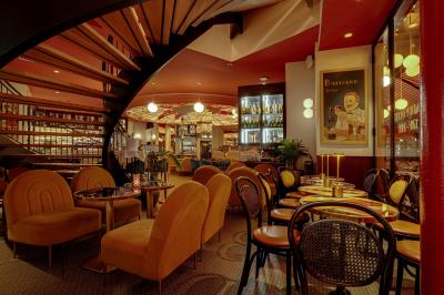 Intérieur d'un restaurant avec des tables, des chaises élégantes, un escalier en colimaçon et une ambiance chaleureuse.