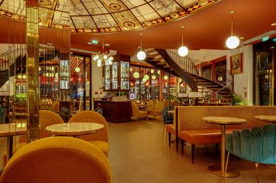 Intérieur d'un restaurant avec des tables, des chaises élégantes, un escalier en colimaçon et une ambiance chaleureuse.