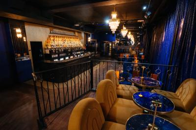 Intérieur d'un restaurant avec des tables, des chaises élégantes, un escalier en colimaçon et une ambiance chaleureuse.