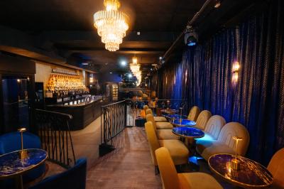 Intérieur d'un restaurant avec des tables, des chaises élégantes, un escalier en colimaçon et une ambiance chaleureuse.