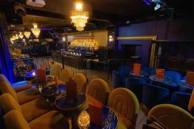 Intérieur d'un restaurant avec des tables, des chaises élégantes, un escalier en colimaçon et une ambiance chaleureuse.