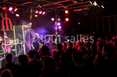 Salle de restaurant en bois avec tables dressées, chaises alignées et lumière naturelle entrant par de grandes fenêtres.