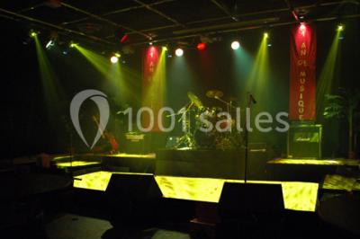 Salle de restaurant en bois avec tables dressées, chaises alignées et lumière naturelle entrant par de grandes fenêtres.