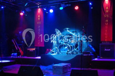 Salle de restaurant en bois avec tables dressées, chaises alignées et lumière naturelle entrant par de grandes fenêtres.