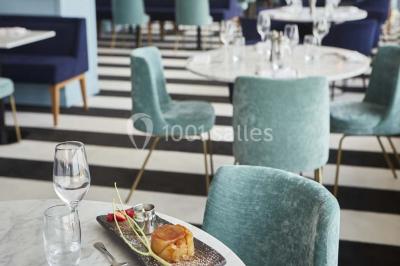 Vue d'une côte avec des falaises, des bâtiments en bord de mer et un ciel partiellement nuageux au crépuscule.