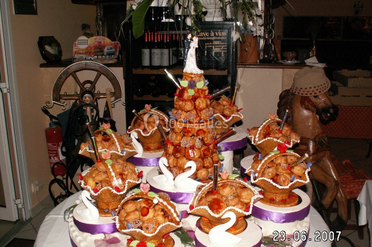 Pièce montée en choux décorée de cygnes en sucre et de fleurs, présentée sur une table festive.