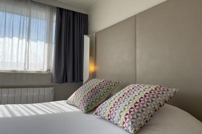 Salle de bain avec douche à paroi vitrée, lavabo suspendu, miroir éclairé et sol en carrelage foncé.