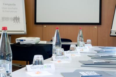 Salle de bain avec douche à paroi vitrée, lavabo suspendu, miroir éclairé et sol en carrelage foncé.