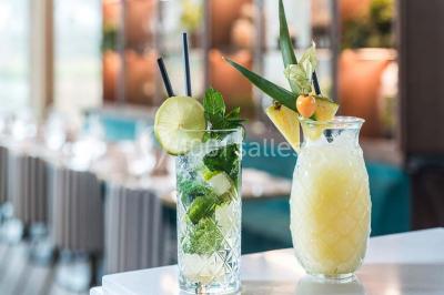 Bâtiment moderne en bord de rivière, entouré de verdure, avec un pont piétonnier au premier plan.