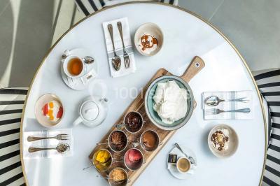 Bâtiment moderne en bord de rivière, entouré de verdure, avec un pont piétonnier au premier plan.