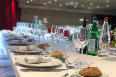 Bâtiment moderne en bord de rivière, entouré de verdure, avec un pont piétonnier au premier plan.