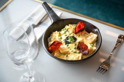 Bâtiment moderne en bord de rivière, entouré de verdure, avec un pont piétonnier au premier plan.